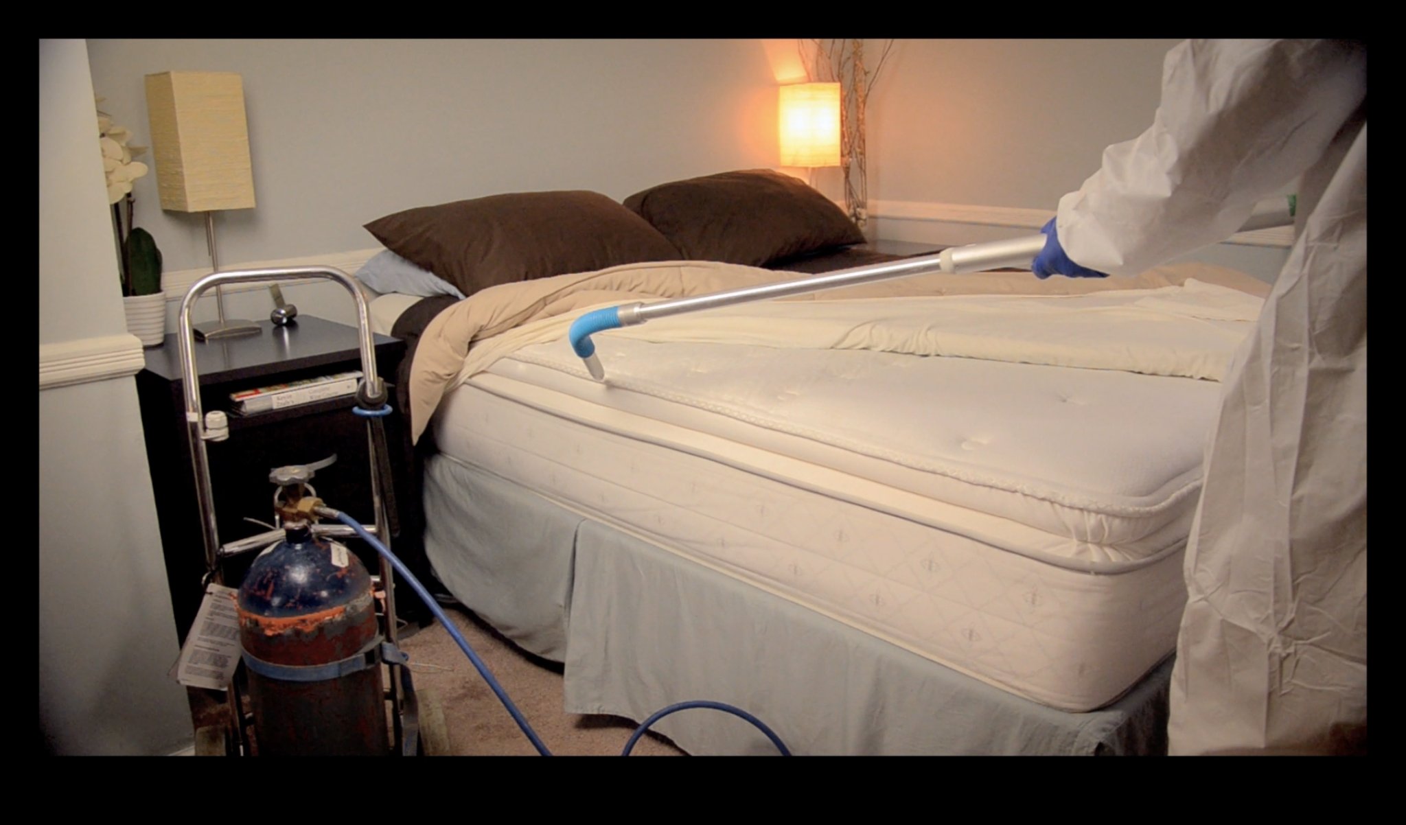 Technician applying Cryonite CO₂ freeze treatment to a mattress for bed bug elimination